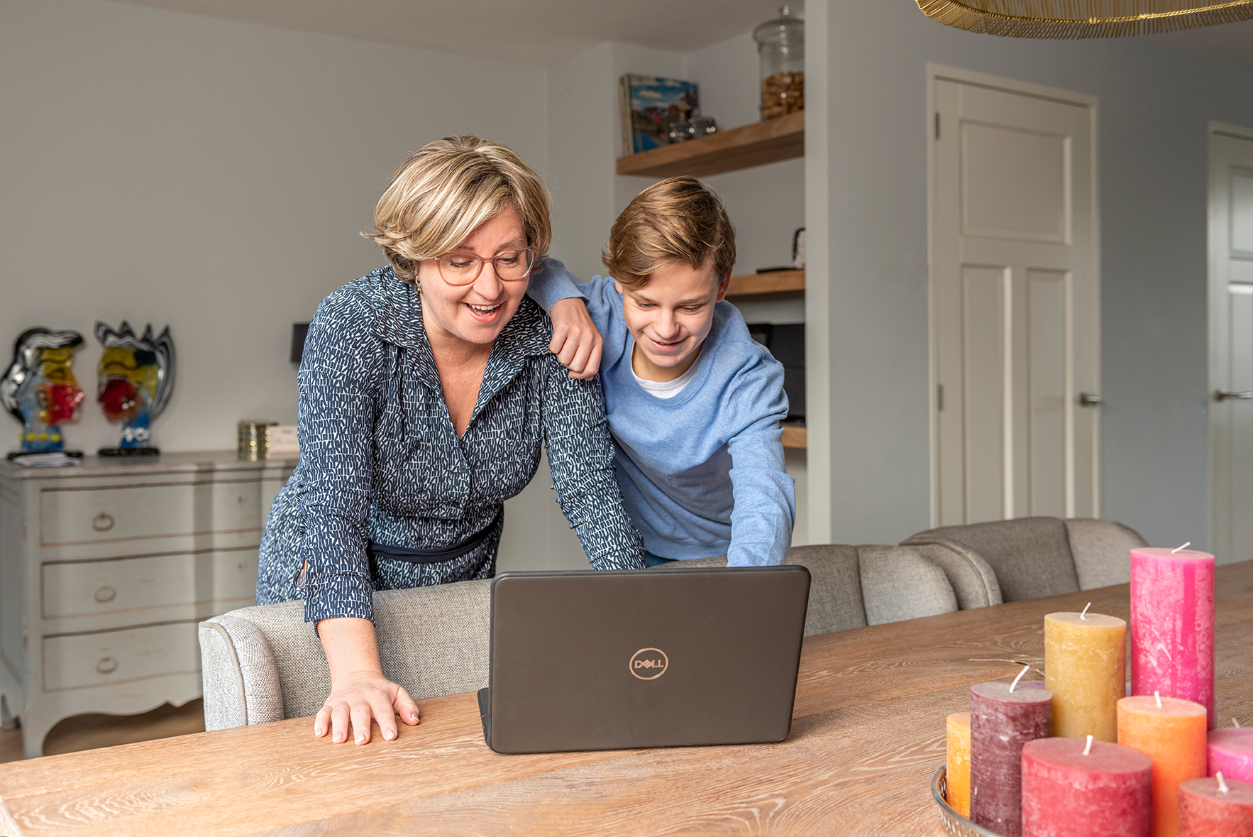 Timo laat iets op de laptop zien aan zijn moeder; ze moeten er allebei om lachen.