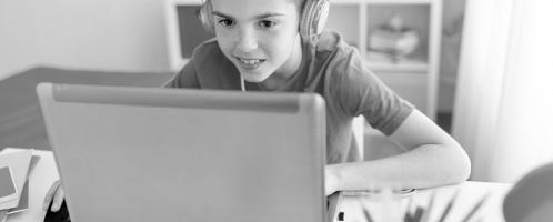 jongen met koptelefoon achter een laptop