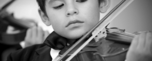 Kind bespeelt een viool en houdt de ogen gesloten.